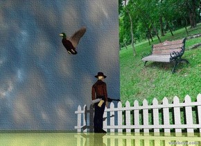 the [garden] wall is 5 feet wide. the ground is shiny grass. the small bird is 5.5 feet in front of the wall. it is 2.5 feet above the ground. it is cloudy. the small fence is 1 foot in front of the wall. it is 10 feet wide. the very small man is 3 feet in front of the fence. He is facing the wall. the small gun is -1.7 inches to the right of the man.  it is 10 inches above the ground. it is facing left.
