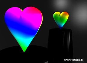 A [rainbow] heart is on a black table. the Sky is black.ground is silver. There is a large light on the heart. There is a large rainbow light facing the table. there is an enormous mirror 2 feet behind the table. the mirror is 30 centimeters in the ground.