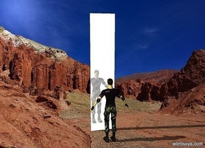 a cube.the cube is 2 inches deep.the cube is 2.5 feet wide.the cube is 12 feet tall.the cube is shiny metal.the sky is white.desert backdrop.a man is 2 feet in front of the cube.he is facing the cube.